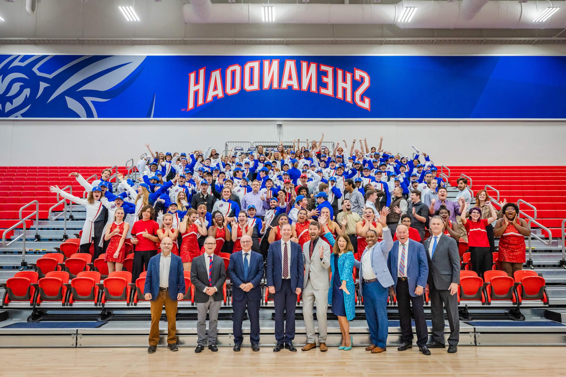 Shenandoah University Marching Band, cheerleaders, Studio Big Band, representatives from Shenandoah University, and organizers of London's New Year's Day Parade pose for a group photo in the Wilkins Athletics & Events Center